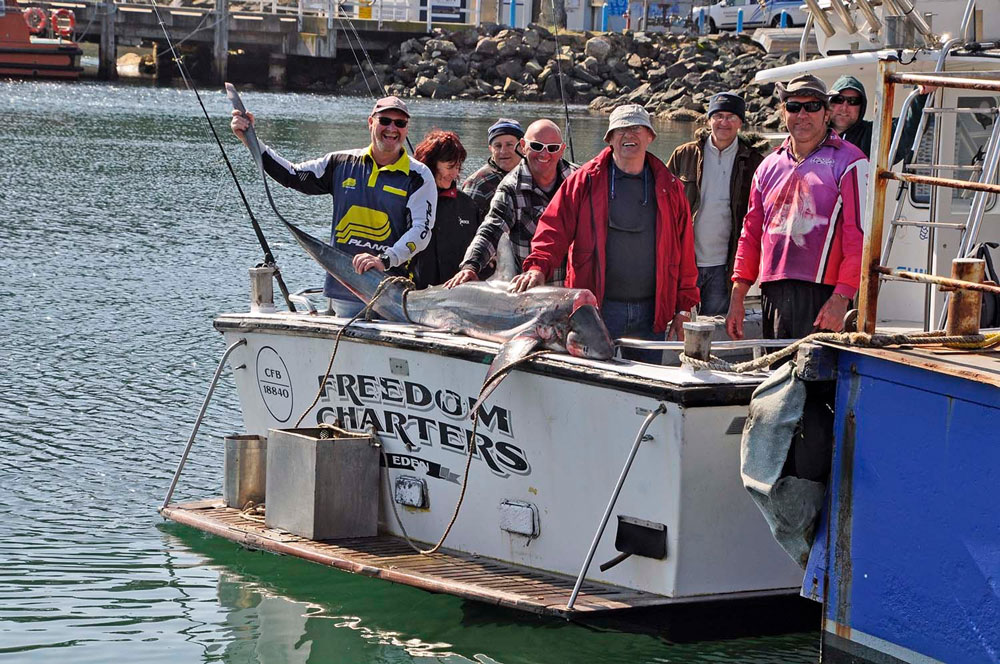 Happy customers on board Freedom Charters with a thresher shark